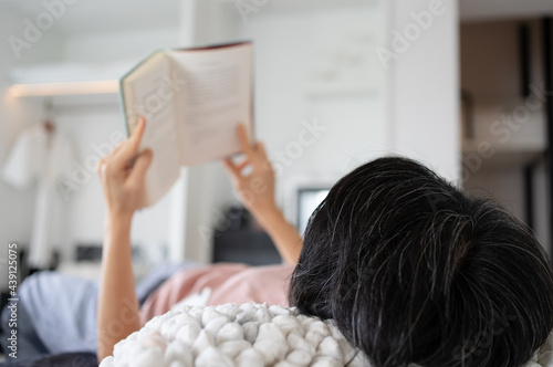 middle age wowan lying on bed and reading book in hotel during vacation photo
