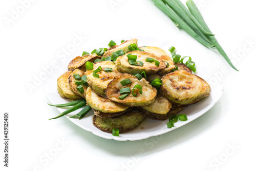 fried zucchini in circles with fresh herbs in a plate isolated on white