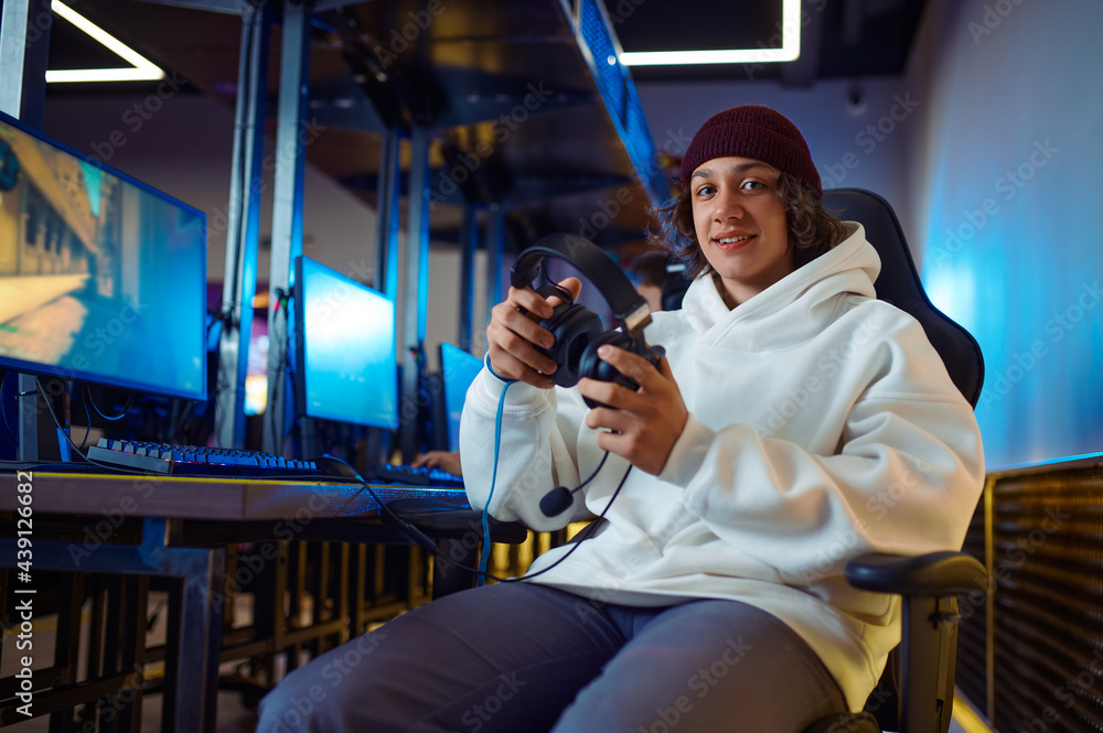 Obraz premium Young cheerful gamer holds headset in game club