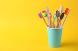 Lots of bamboo eco toothbrushes on yellow background