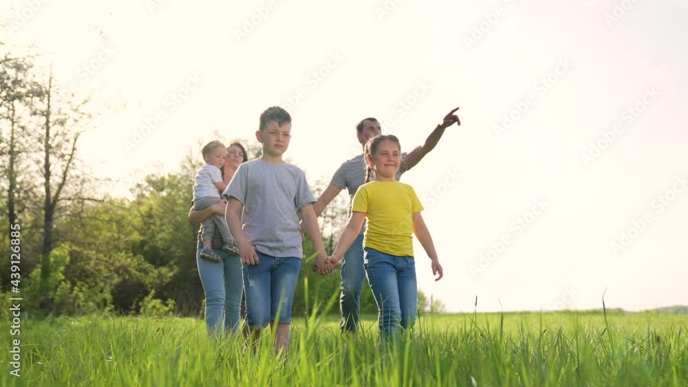 Happy family. Parents and child walk in park. People walk in nature. Happy family in green field. Parents and child in nature at sunset. Happy family concept. Group of people in green grass in park Happy family. Parents and child walk in park. People walk in nature. Happy family in green field. Parents and child in nature at sunset. Happy family concept. Group of people in green grass in park