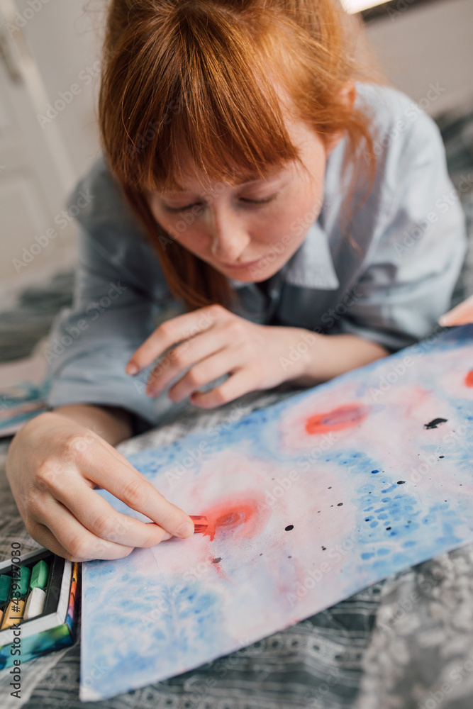 Ginger woman holding crayons and drawing carefully at home Ginger woman holding crayons and drawing carefully at home