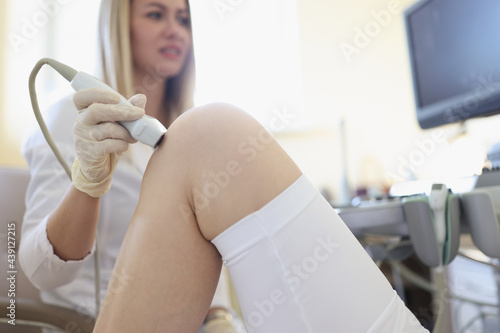 Ultrasound examination of knee joint is carried out by doctor in office photo