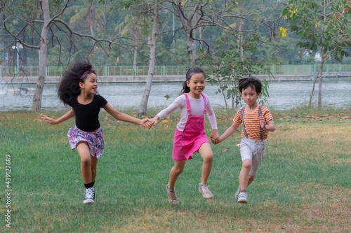 Adorable children running competition with fun in green park on holiday, group of primary school friendship laughing play in garden, Healthy Afro mix race girl and Asian kids spent time with nature
