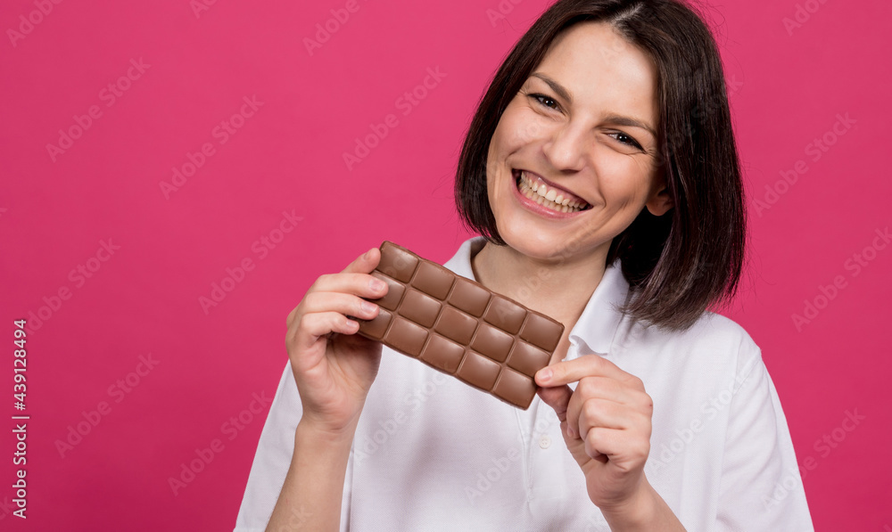 Beautiful young woman holding a bar of chocolate in her hand Beautiful young woman holding a bar of chocolate in her hand