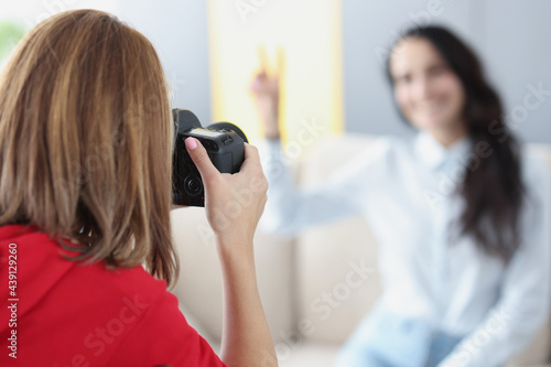 Woman photographer takes pictures of girl on couch
