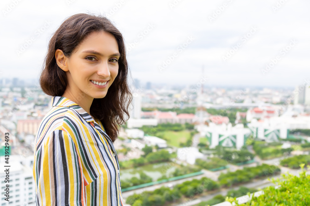 Happy beauty Caucasian young woman with high building and cityscape background Attractive beautiful girl has nice smile Get relax, enjoy life with happiness Lovely lady portrait She look at camera