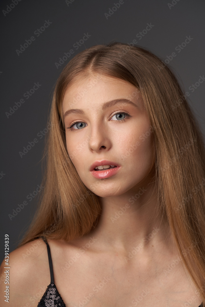 Natural portrait of young beautiful teen age girl with long straight hair. Female model studio shot against grey background. Pretty girl Natural portrait of young beautiful teen age girl with long straight hair. Female model studio shot against grey background. Pretty girl