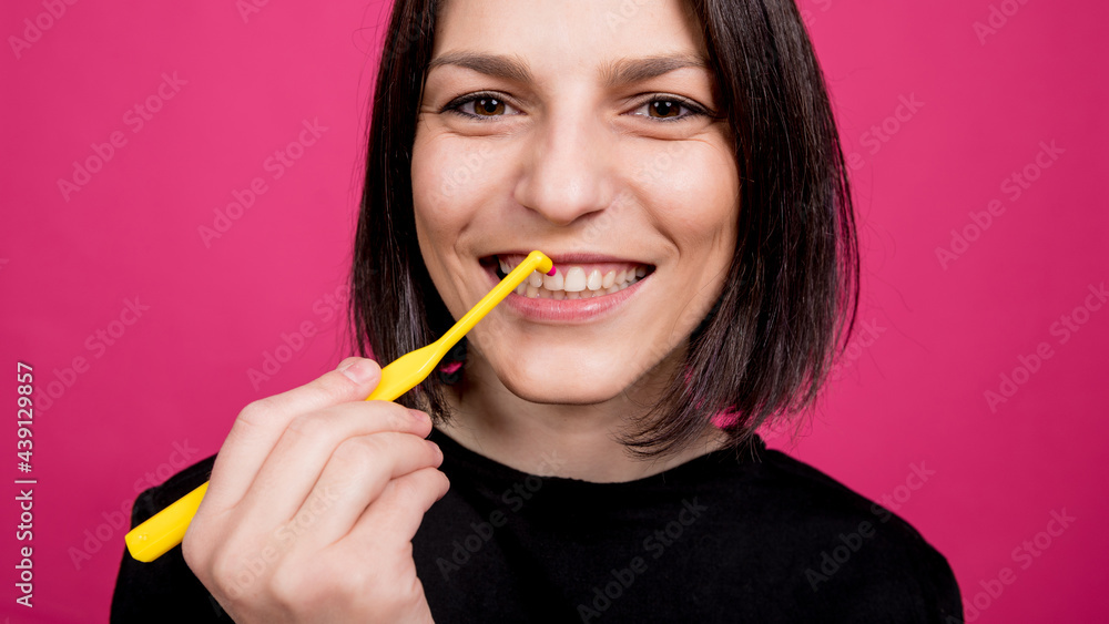 Beautiful happy young woman with single tufted toothbrush on blank pink background Beautiful happy young woman with single tufted toothbrush on blank pink background