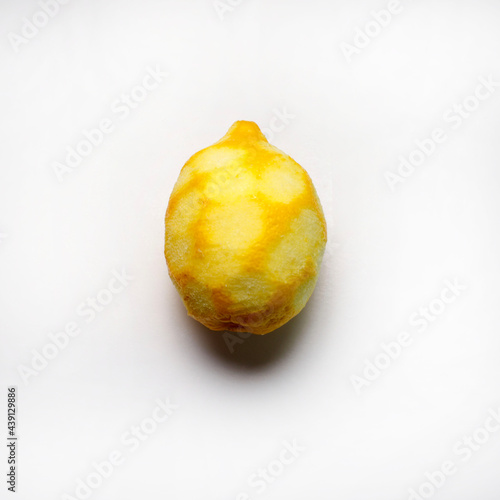 Un limone con la buccia grattugiata isolato su sfondo bianco. Direttamente sopra.