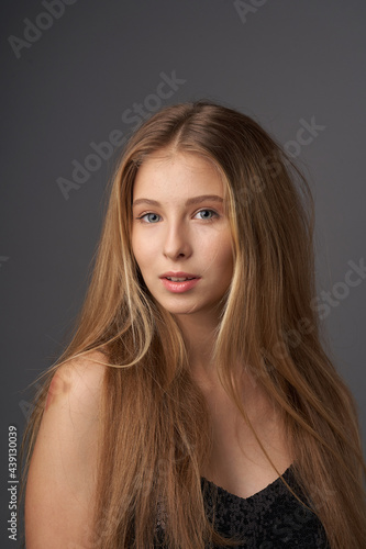 Natural portrait of young beautiful teen age girl with long straight hair. Female model studio shot against grey background. Pretty girl