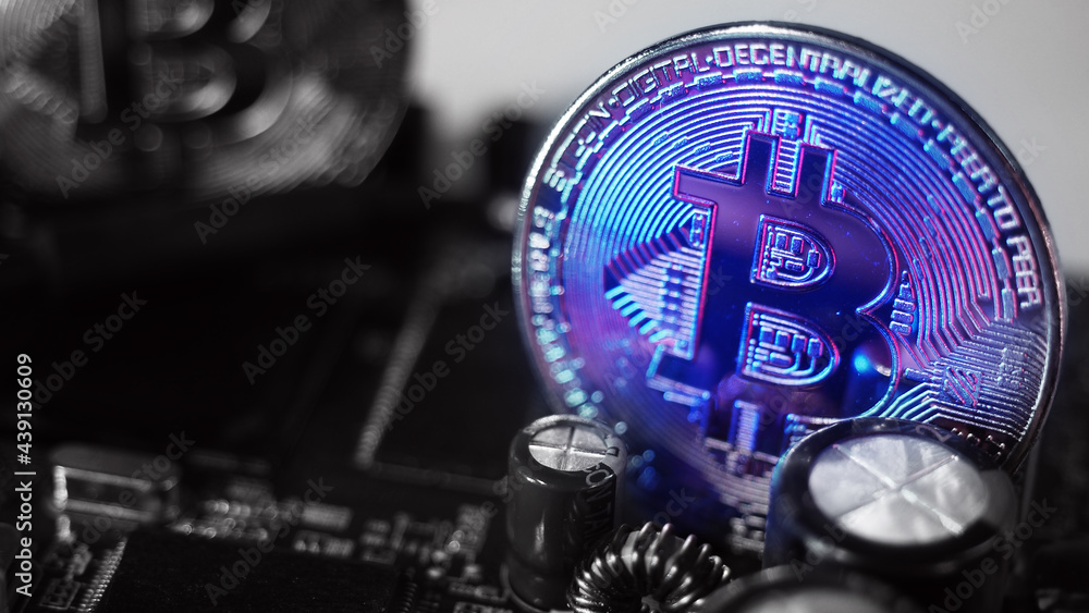 Fototapeta premium Bitcoin and semiconductor. Represent mining in Cryptocurrency cause global warming. Bitcoins on CPU board. Close-up Bitcoin with blue and pink light. circuit board with coin. Online asset concept.