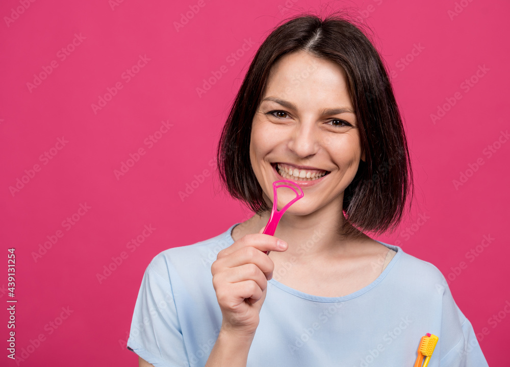 Beautiful happy young woman with tongue scraper on blank pink background Beautiful happy young woman with tongue scraper on blank pink background