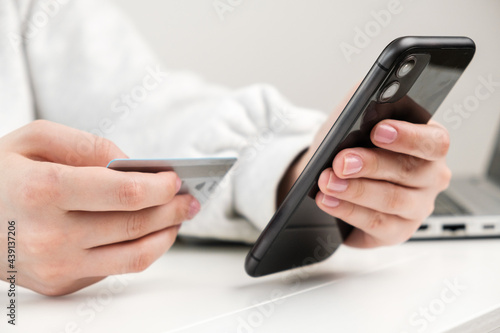 Close up woman hand holding credit card and smartphone for making purchase in online shop