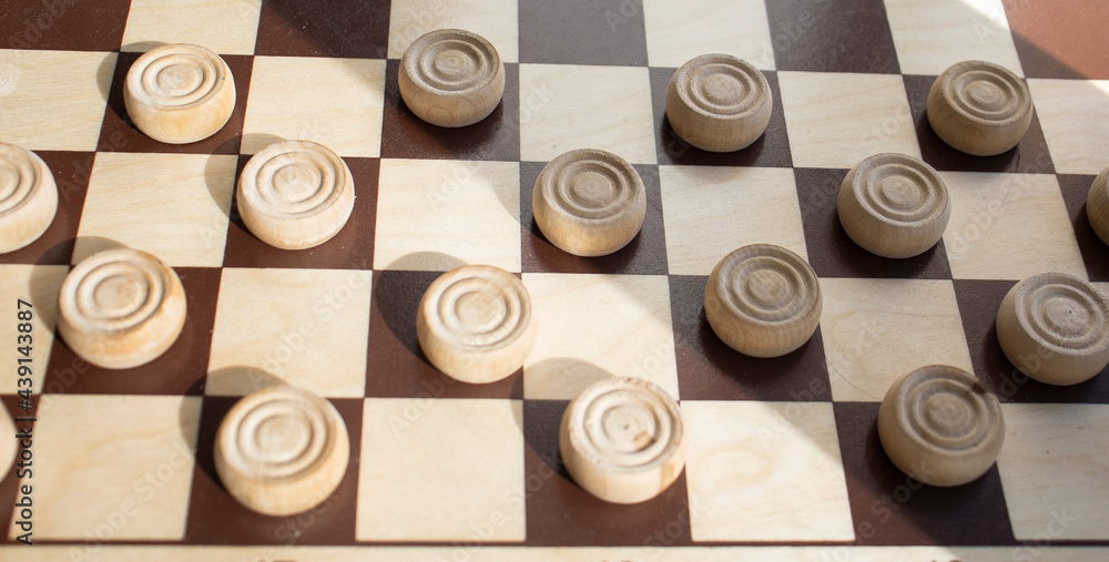 Fototapeta premium wooden chessboard with white checkers on a light surface. Mind games, mental development and strategy. Games for children and adults. Chess school