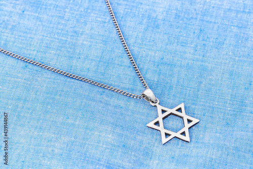 Star of David ("Magen David") with chain on white-blue fabric.