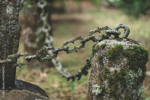 weathered chain of iron and granite columns at a grave in a cemetery