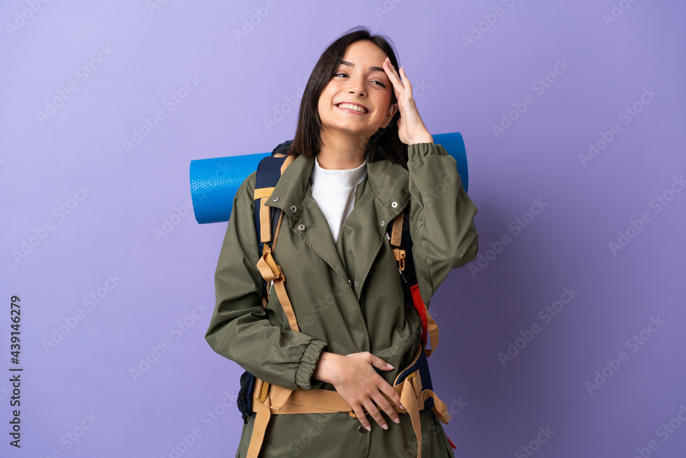 Young mountaineer woman with a big backpack over isolated background smiling a lot Young mountaineer woman with a big backpack over isolated background smiling a lot