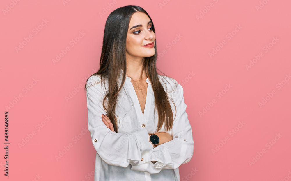 Young beautiful woman wearing casual white shirt looking to the side with arms crossed convinced and confident Young beautiful woman wearing casual white shirt looking to the side with arms crossed convinced and confident