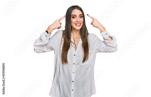 Young beautiful woman wearing casual white shirt smiling pointing to head with both hands finger, great idea or thought, good memory