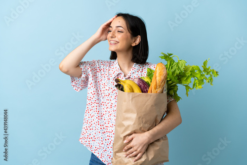 Young woman holding a grocery shopping bag smiling a lot
