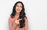 Hispanic teenager girl with dental braces wearing casual clothes cheerful with a smile of face pointing with hand and finger up to the side with happy and natural expression on face