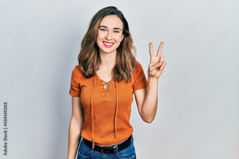 Young hispanic girl wearing casual clothes smiling with happy face winking at the camera doing victory sign. number two. Young hispanic girl wearing casual clothes smiling with happy face winking at the camera doing victory sign. number two.
