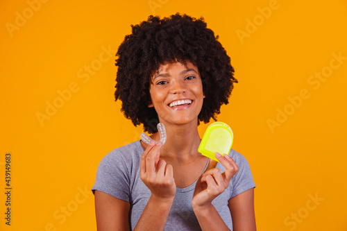 afro woman holding whitening plate. Invisible device. photo