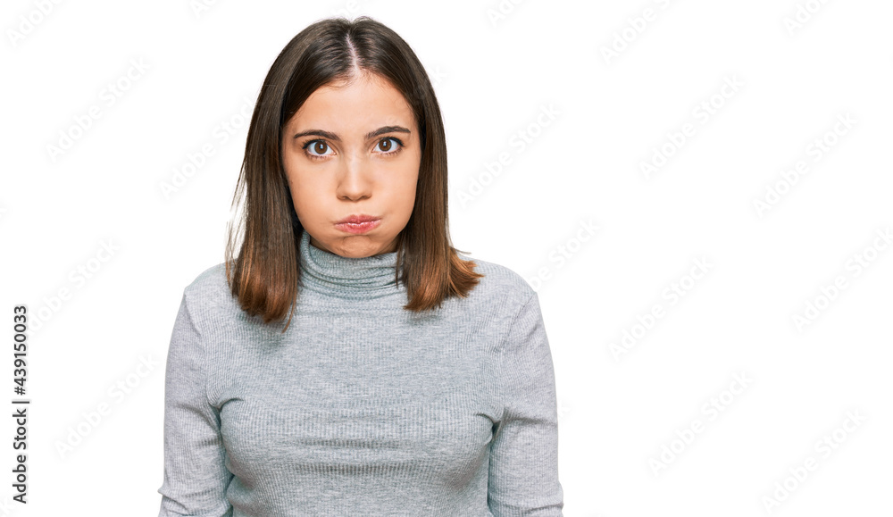 Young beautiful woman wearing casual turtleneck sweater puffing cheeks with funny face. mouth inflated with air, crazy expression. Young beautiful woman wearing casual turtleneck sweater puffing cheeks with funny face. mouth inflated with air, crazy expression.