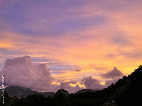 Sunset over a small village, over green hills covered of green forest. Pink stunning beautiful sunset. Heaven with clouds and a multi colored glow of sundown. Horizon view. Twilight, evening panorama.
