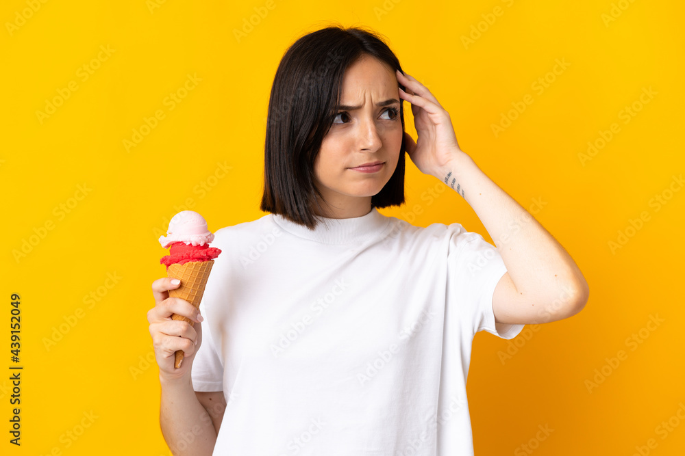 Young caucasian woman with a cornet ice cream isolated on yellow background having doubts and with confuse face expression Young caucasian woman with a cornet ice cream isolated on yellow background having doubts and with confuse face expression