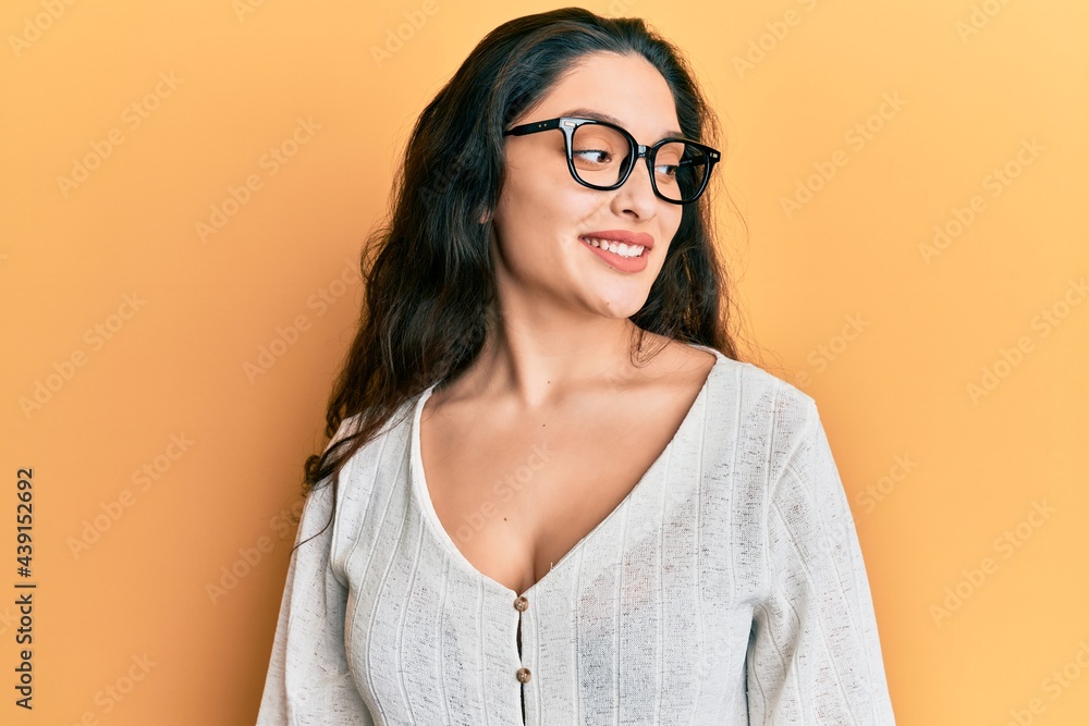 Beautiful middle eastern woman wearing casual clothes and glasses looking to side, relax profile pose with natural face and confident smile.
