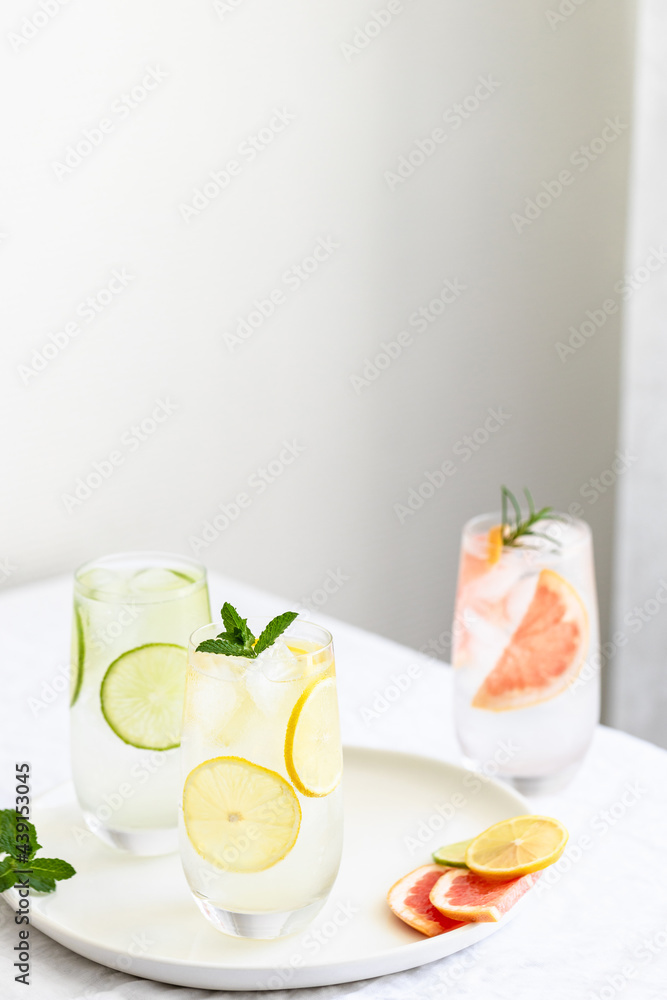 Glasses with cold citrus fruits water with mint and rosemary garnish on plate. Glasses with cold citrus fruits water with mint and rosemary garnish on plate.