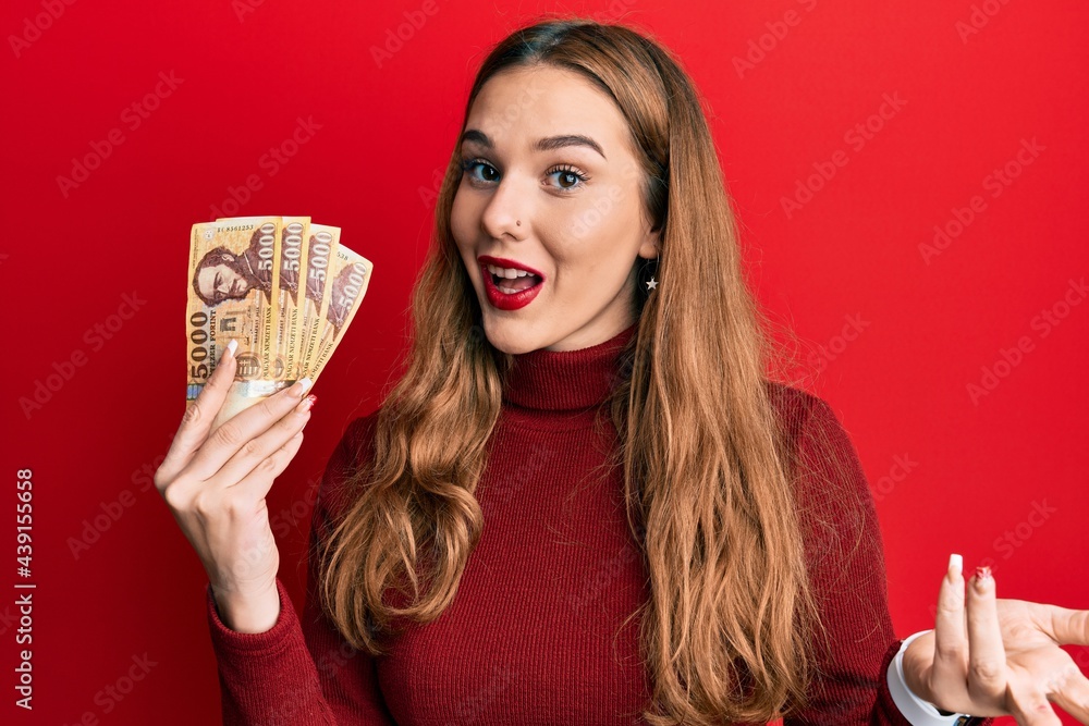 Foto Stock Young Blonde Woman Holding 5000 Hungarian Forint Banknotes Celebrating Achievement