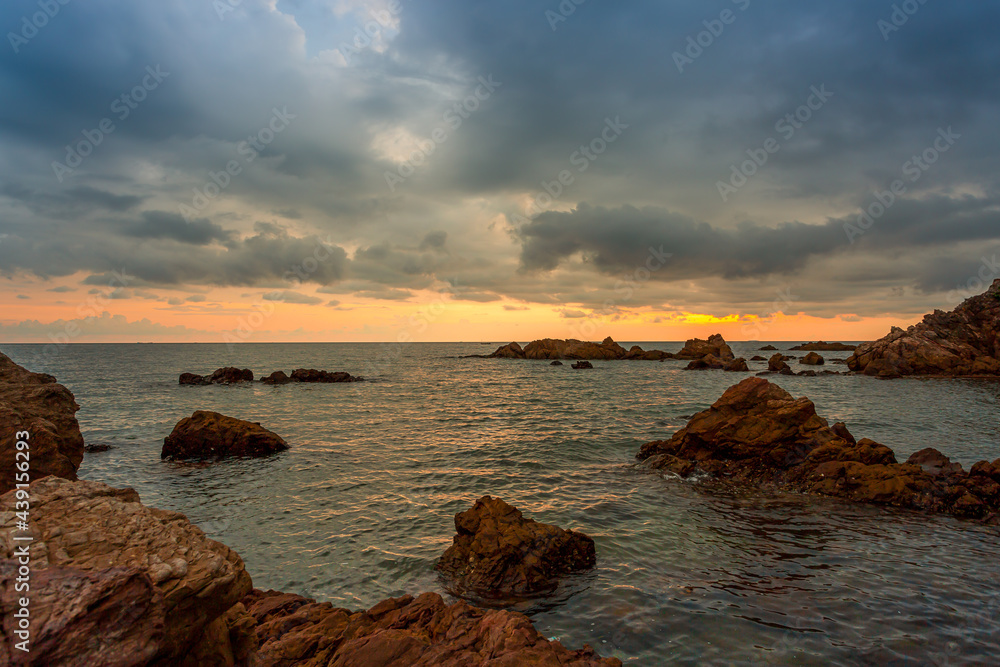 The sea and rocks and the stormy sky,cloudy sunset over the sea in a rocky beach with stones and red dusk. epic sky