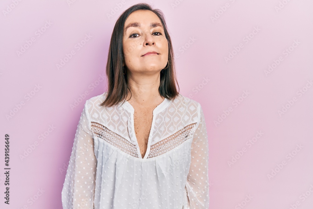 Middle age hispanic woman wearing casual clothes relaxed with serious expression on face. simple and natural looking at the camera. Middle age hispanic woman wearing casual clothes relaxed with serious expression on face. simple and natural looking at the camera.