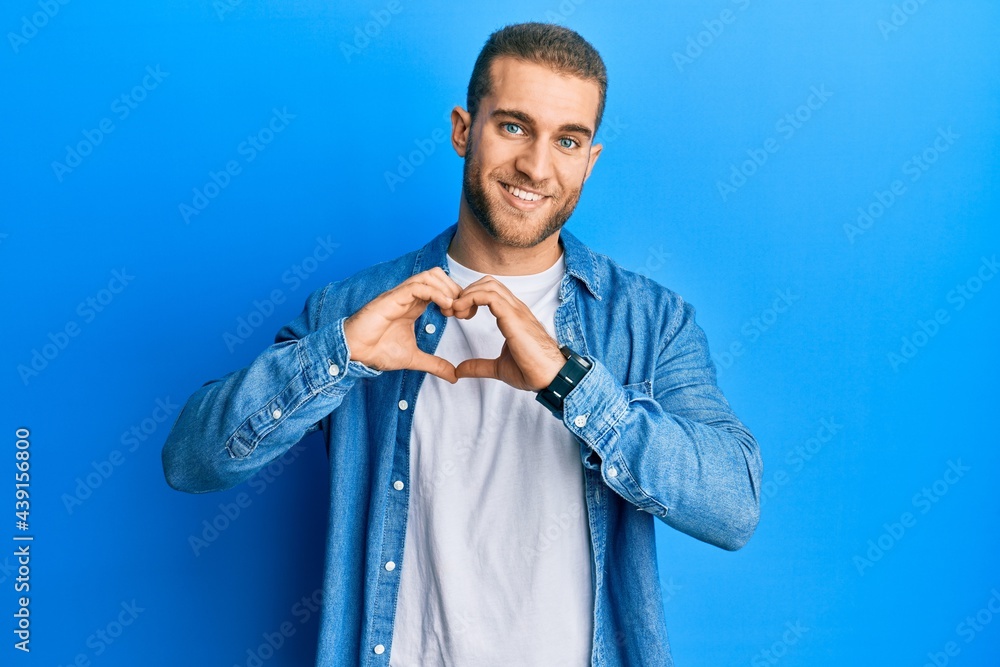 Fototapeta premium Young caucasian man wearing casual clothes smiling in love doing heart symbol shape with hands. romantic concept.