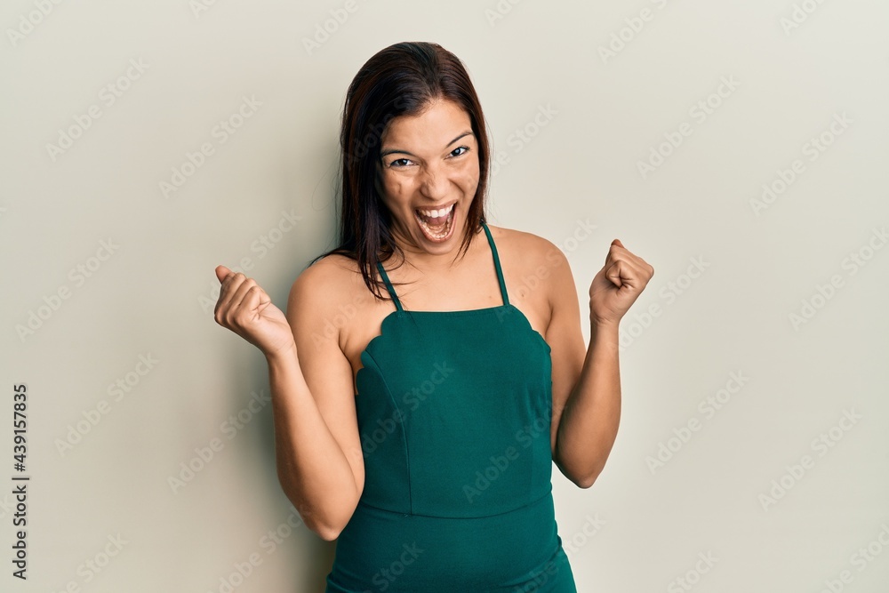 Young latin woman wearing casual clothes screaming proud, celebrating victory and success very excited with raised arms Young latin woman wearing casual clothes screaming proud, celebrating victory and success very excited with raised arms