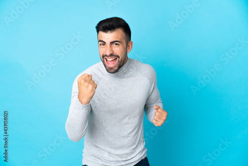 Caucasian man over isolated blue background celebrating a victory