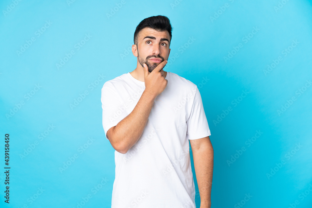 Caucasian man over isolated blue background having doubts Caucasian man over isolated blue background having doubts