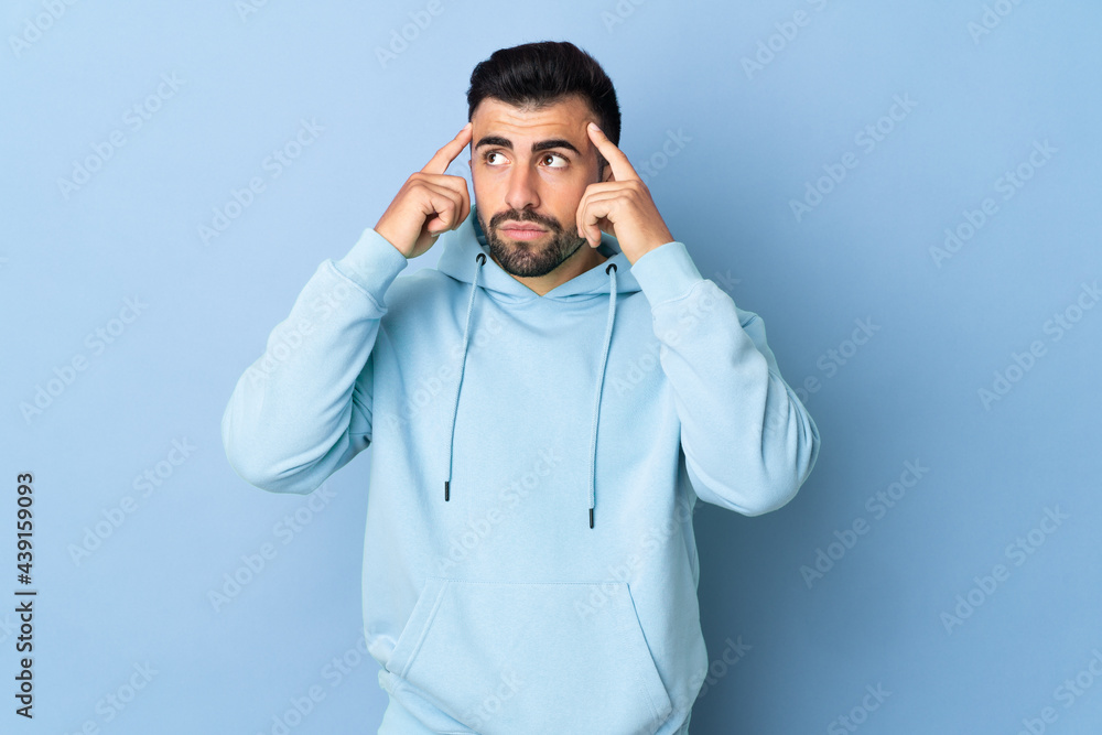Caucasian man over isolated blue background having doubts and thinking Caucasian man over isolated blue background having doubts and thinking