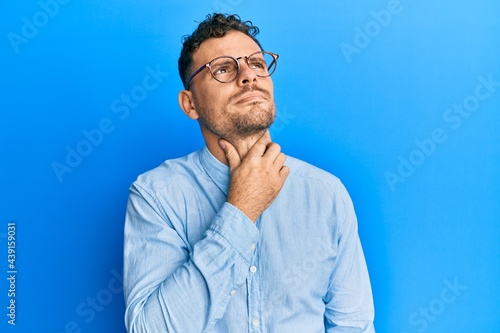 Young hispanic man wearing casual clothes and glasses touching painful neck, sore throat for flu, clod and infection © Krakenimages.com