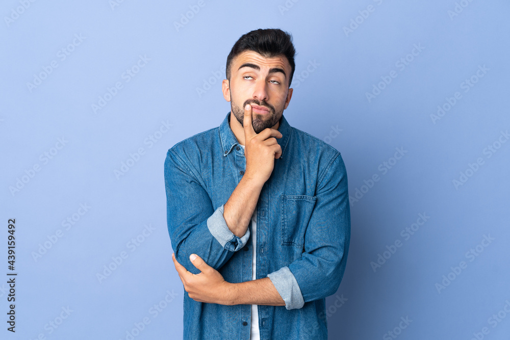Caucasian man over isolated blue background having doubts while looking up Caucasian man over isolated blue background having doubts while looking up