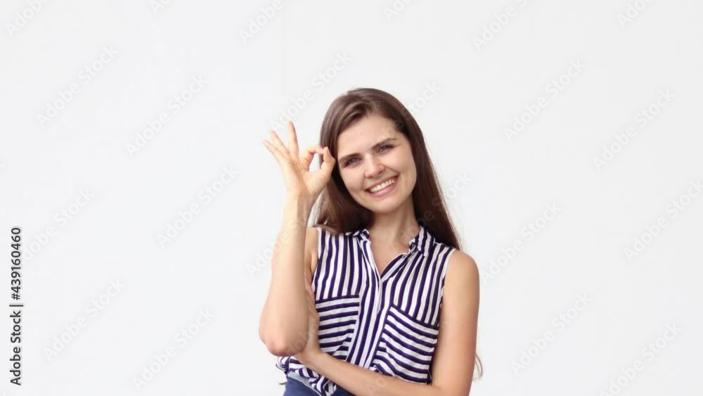 Attractive woman smiles at camera showing hand OK sign on white background. People lifestyle concept. Attractive woman smiles at camera showing hand OK sign on white background. People lifestyle concept.