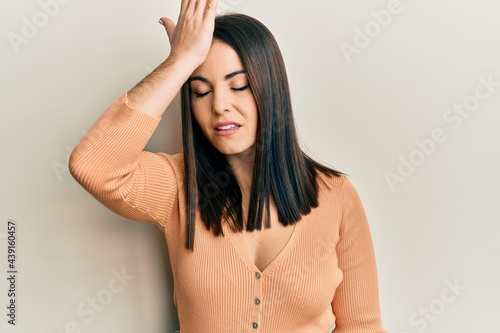 Young brunette woman wearing casual clothes surprised with hand on head for mistake, remember error. forgot, bad memory concept.