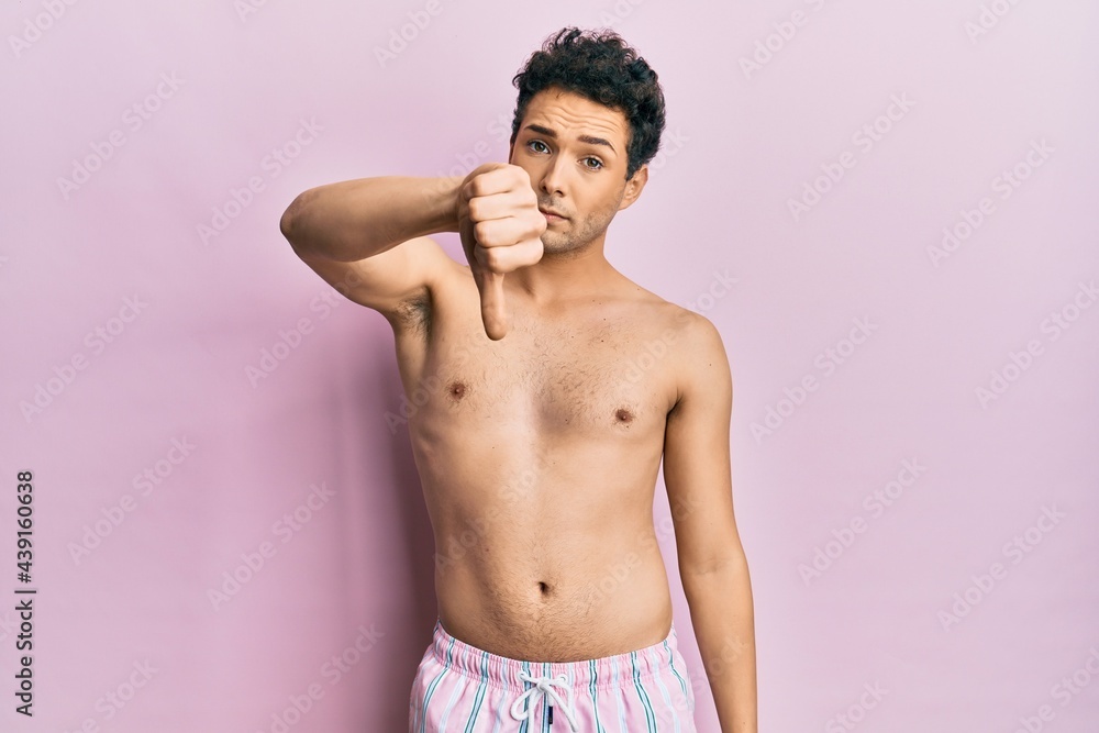 Fototapeta premium Young handsome man wearing swimwear shirtless looking unhappy and angry showing rejection and negative with thumbs down gesture. bad expression.