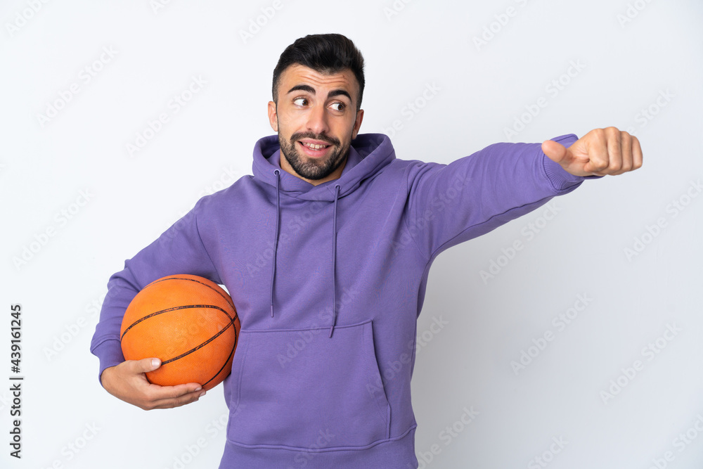 Man playing basketball over isolated white wall giving a thumbs up gesture