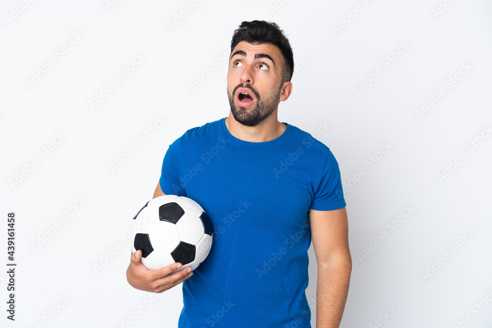 Handsome young football player man over isolated wall looking up and with surprised expression Handsome young football player man over isolated wall looking up and with surprised expression