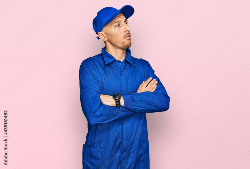 Bald man with beard wearing builder jumpsuit uniform looking to the side with arms crossed convinced and confident Bald man with beard wearing builder jumpsuit uniform looking to the side with arms crossed convinced and confident