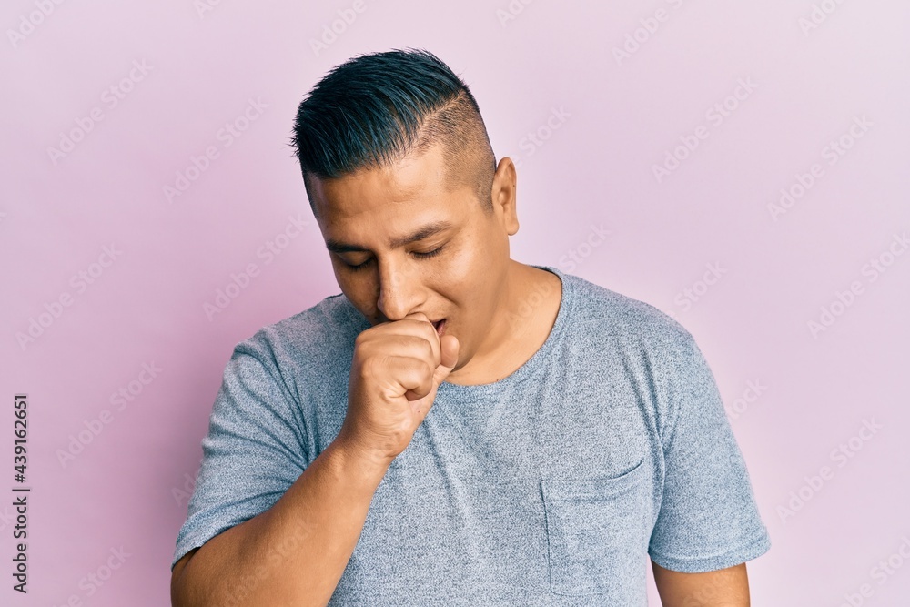 Young latin man wearing casual clothes feeling unwell and coughing as symptom for cold or bronchitis. health care concept. Young latin man wearing casual clothes feeling unwell and coughing as symptom for cold or bronchitis. health care concept.